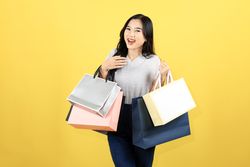 Asian Happy Female Woman Girl Holds Colourful Shopping Bags Standing on Yellow Background