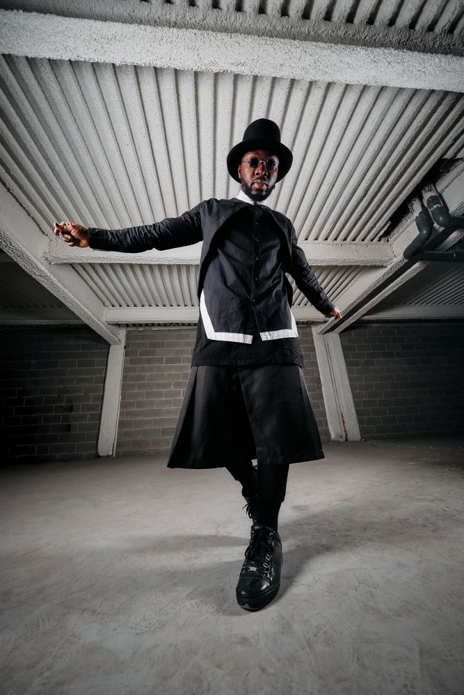 Stylish Black man in round sunglasses and hat standing in under