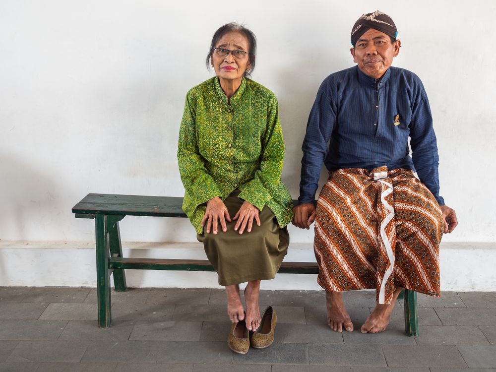 Java Island, Indonesia - August, 14 2015: Barefoot people on bench in palace yard