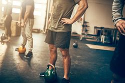 People standing in the gym with kettlebells at their feet