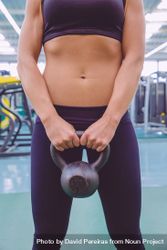 Torso of fit woman holding kettle bell 49jRLb