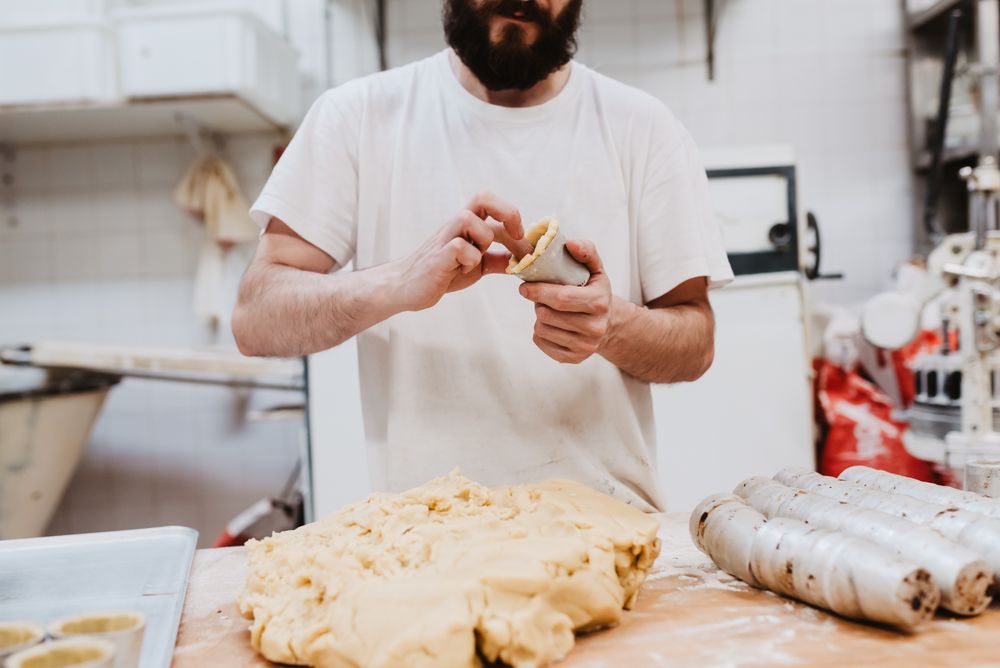 Unrecognizable cook putting pastry dough in cup