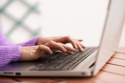 Hands of woman typing on laptop keyboard