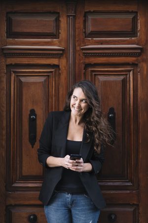 Young female using mobile phone on wooden door