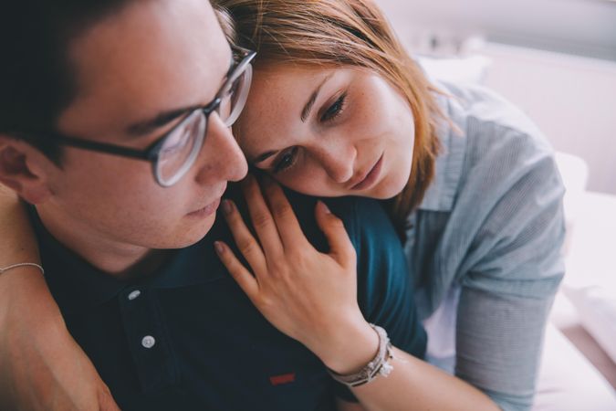 Young woman leaning affectionately onto young man’s shoulder
