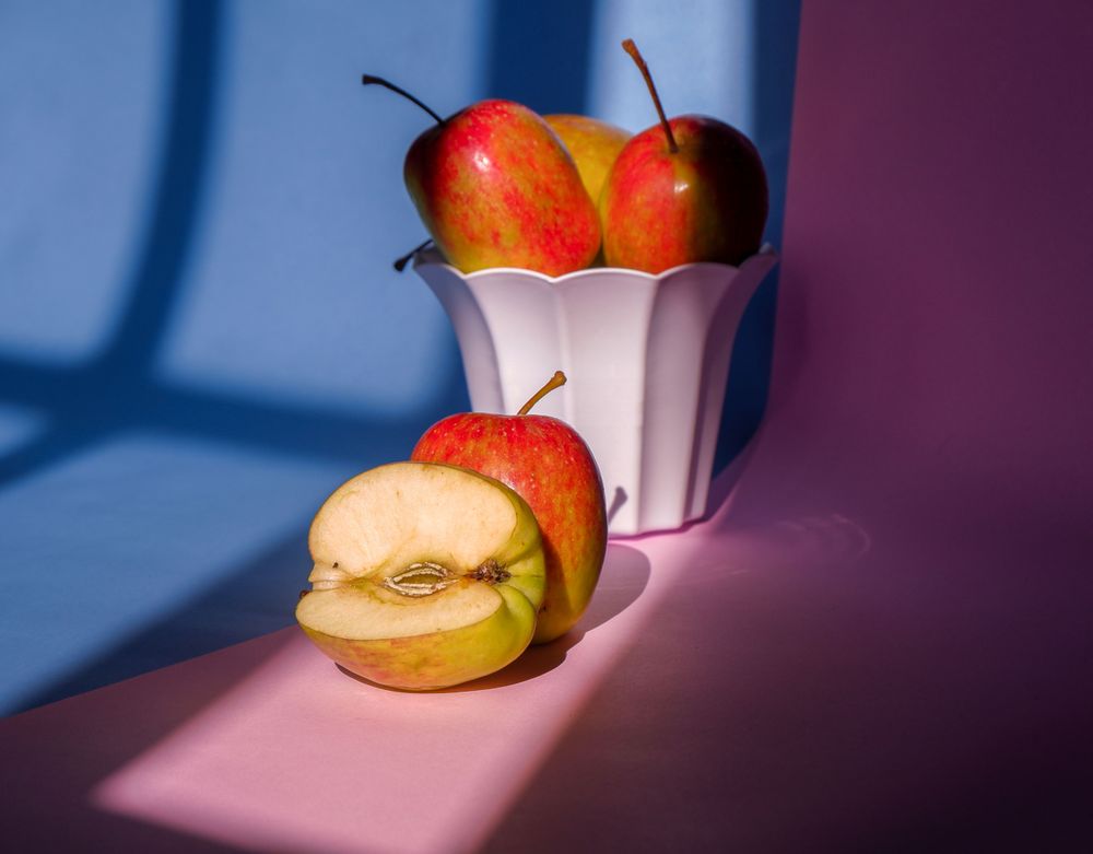 Photo of an apple in a container on a pink and blue background