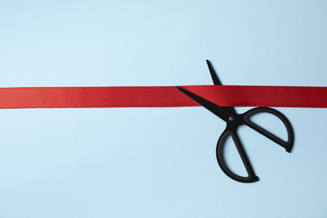 scissors and red ribbon on blue background