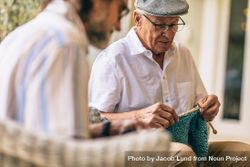 Two old men sitting knitting warm clothes 487BY5