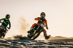 Motocross riders racing motorcycles in desert 0ynpj5