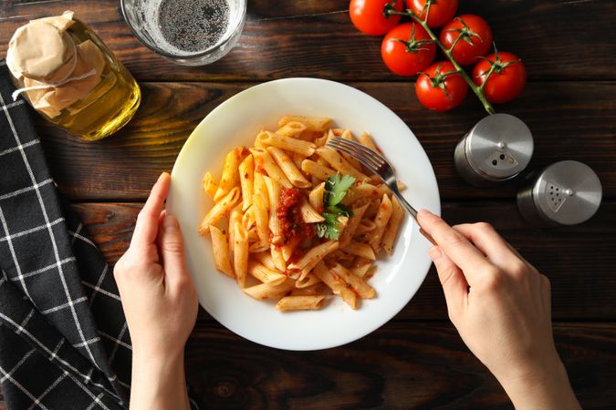 Woman eats tasty pasta. Composition with pasta on wooden background