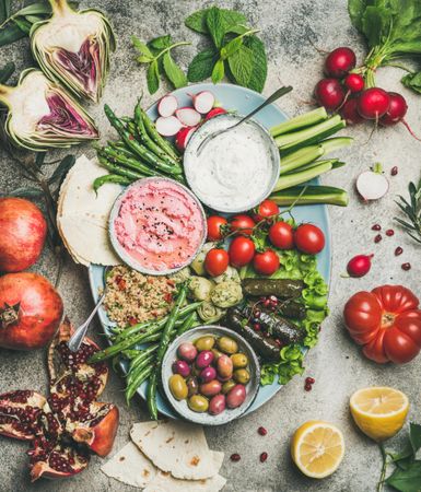 Fresh tray of vegetarian snacks with fresh vegetables, olives, hummus, and dolmas
