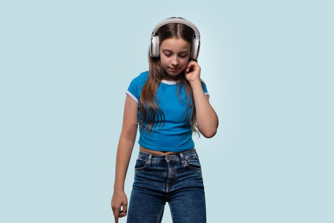 Girl in blue shirt and jeans listening to music