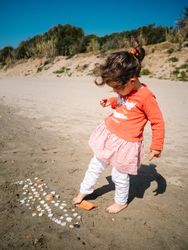 Cute girl playing with seashells on beach