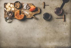 Cheese plate with glasses of red wine being poured, with copy space