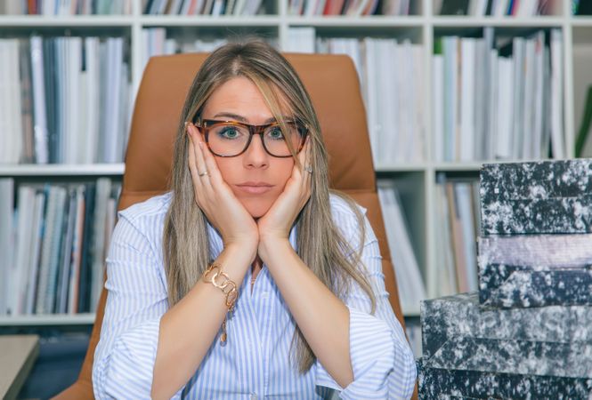 Overwhelmed woman next to box of documents in office
