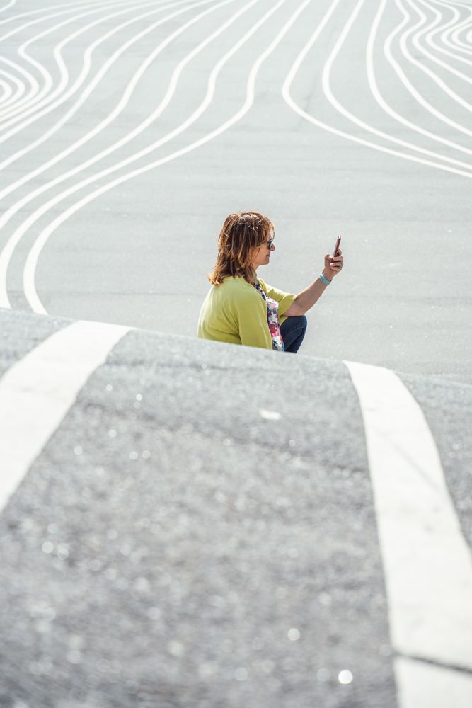Modern relaxed woman on marked road and browsing smartphone