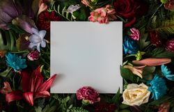 Colorful spring flowers of red, blue, pink, cream around paper square on dark background