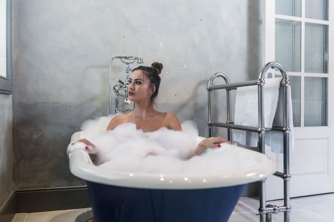 Woman in laying in foamy bathtub
