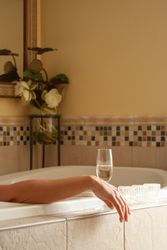 Woman Relaxing in the Bathroom Spa Tub with a Glass of Sparkling Champagne and Candles.
