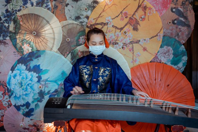 Chinese woman with facemask playing guzheng