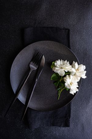 Top view of minimalistic table setting with flowers on plate with cutlery