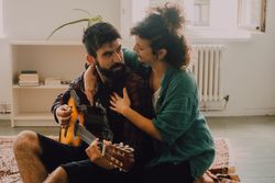 Cheerful couple playing guitar at home