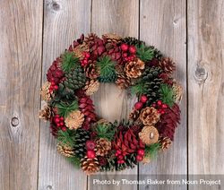 Holiday pine cone wreath on rustic wood bepQp4