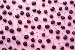 Many cherries scattered over a pink background