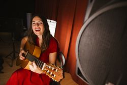Creative woman singing and playing guitar on stage
