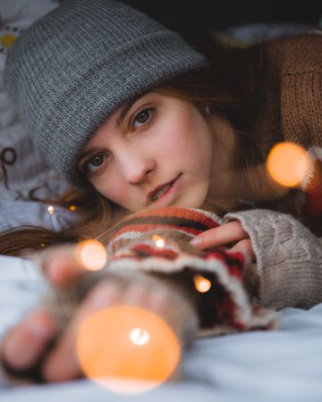 Young woman with gray knit cap laying near bokeh light