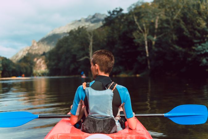 Female kayaking with paddle in raised hands