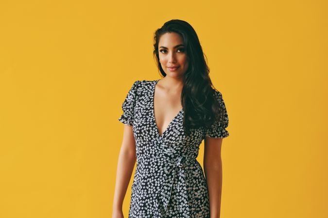 Hispanic woman wearing dress standing in yellow room