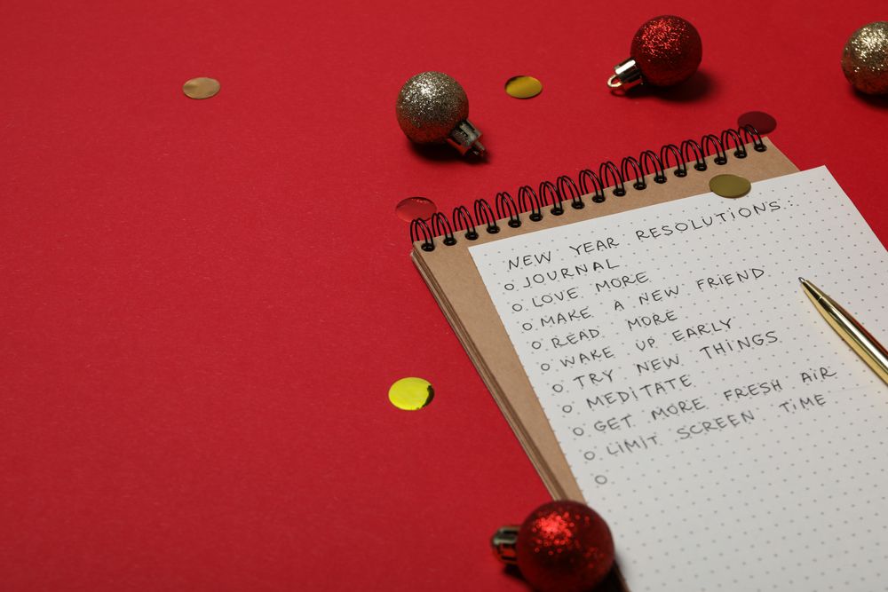 Notepad and paper with list on red background, space for text