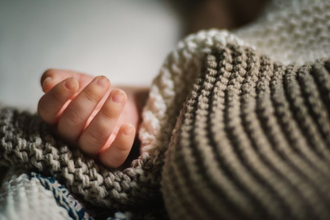 Crop baby hand near blanket