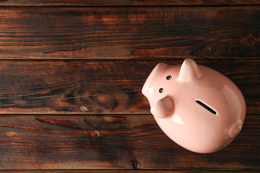 Happy piggy bank on wooden background, space for text and top view. Finance, saving money