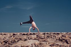 Flexible young man performing two hands rotation while dancing breakdance