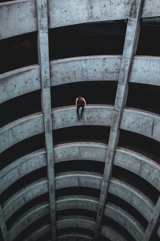 Man sitting on rail of circular parking garage
