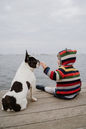 kid petting dog on pier