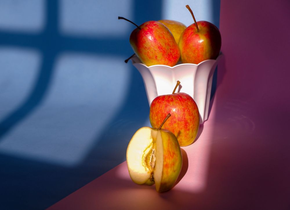 Photo of an apple in a container on a pink and blue background