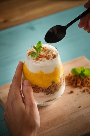 Crop woman eating cheesecake from glass