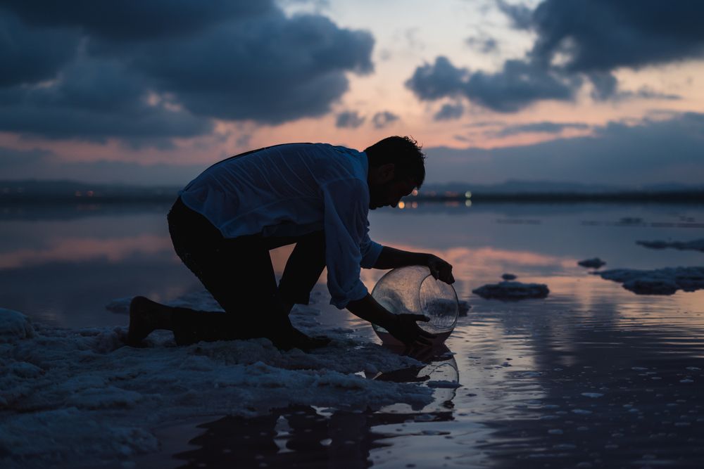 Focused man filling fish tank with water from sea in dusk