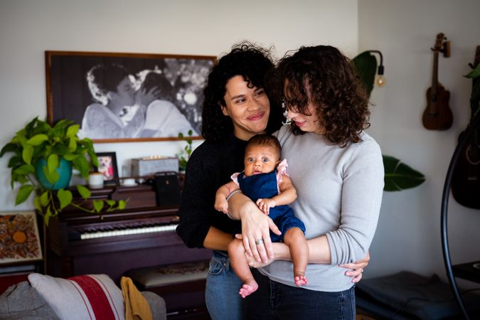 Content couple with their baby daughter in the living room, vertical