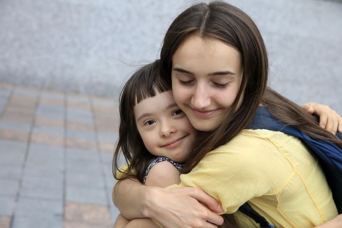 Adult sister giving a hug to her younger sister