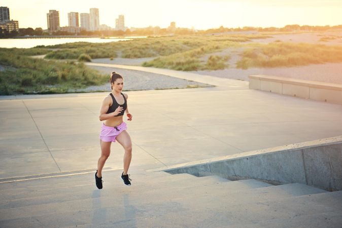 Muscular woman running up stairs in morning light