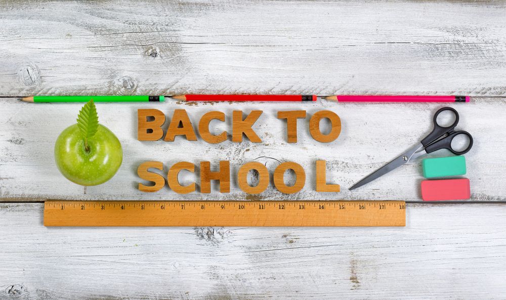 Back to school letters with apple and supplies on top of old wooden boards