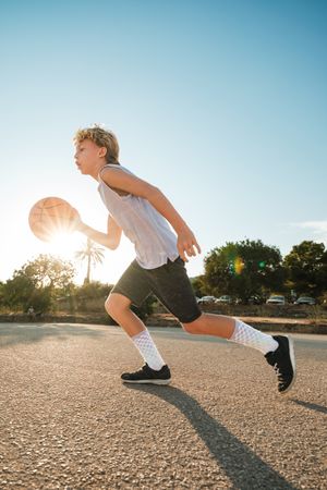 Active kid running with ball on sunny day