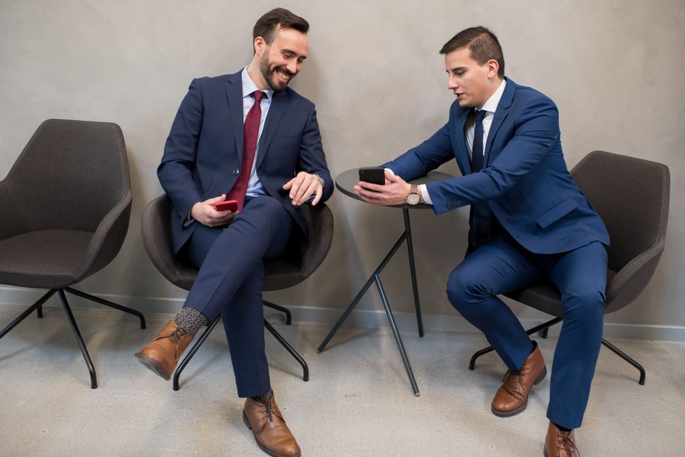 Trendy businessmen sharing smartphone in leisure
