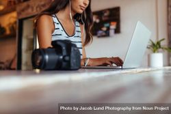 Woman blogger using laptop at home wearing earphones 4jWERb