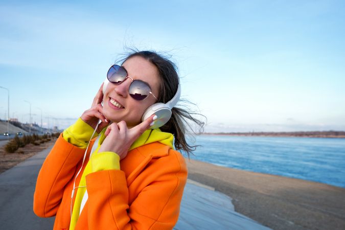 Woman in colorful clothes wearing headphones on the coast