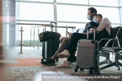 Couple wearing face masks sitting at airport terminal and waiting for the flight 0yaEq0